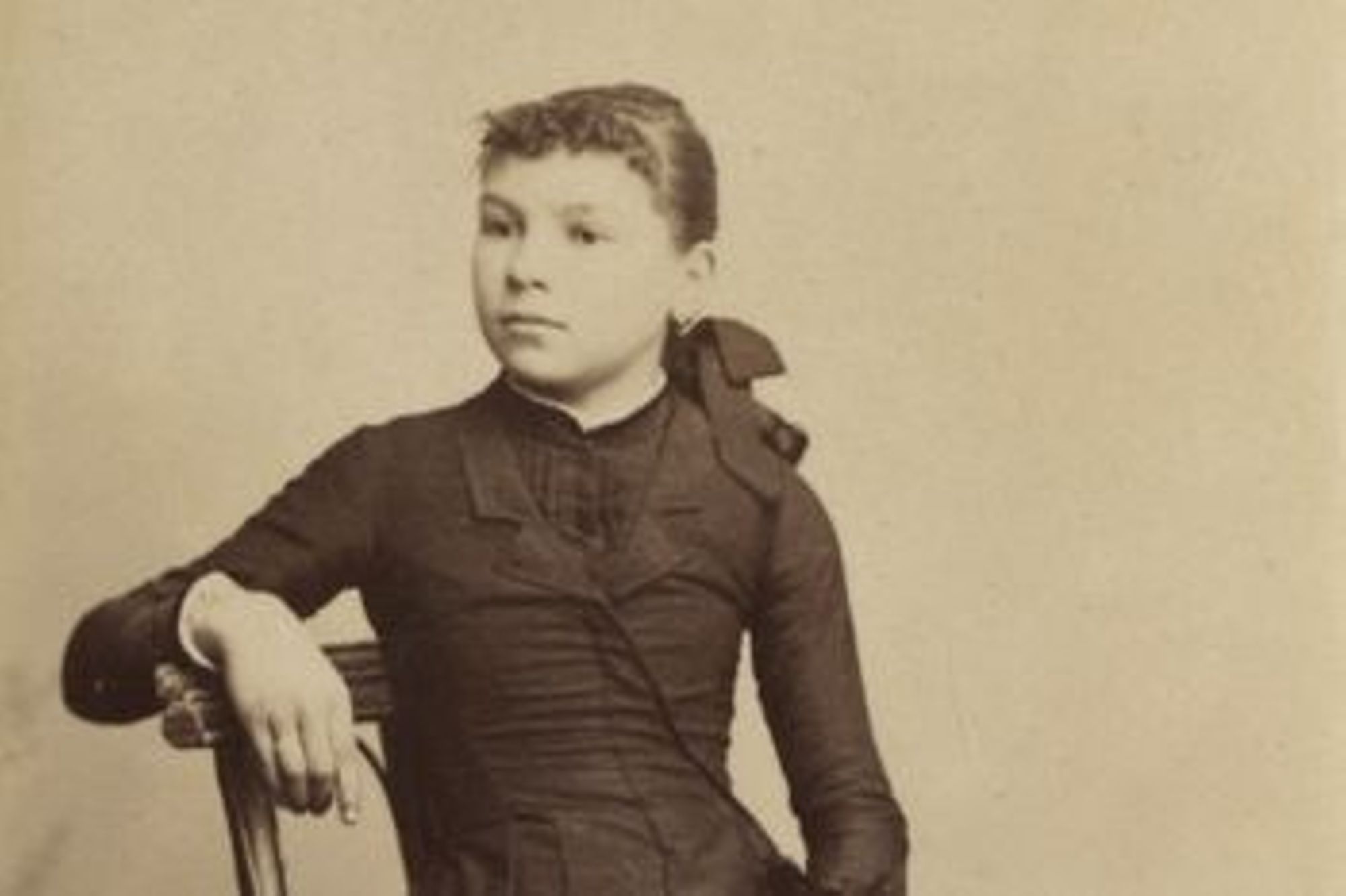 Jeune fille assise, tenant une photo dans la main gauche. (Arch. dép. du Loiret, 7 FI 19)